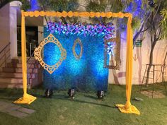 a blue and yellow backdrop with flowers on the grass in front of a building at night