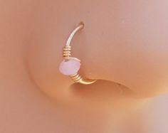 a close up view of a nose ring with a pink stone on the inside of it