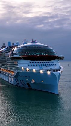 a large cruise ship in the ocean with lights on