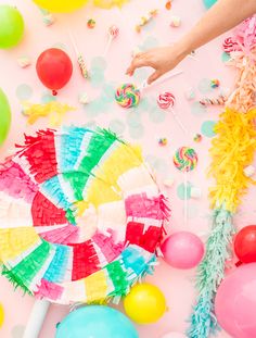 colorful party supplies and balloons on a pink background