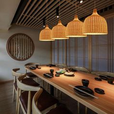 a wooden table topped with lots of plates and bowls under hanging light fixture lights over it