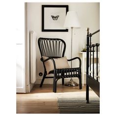 a black chair sitting next to a lamp on top of a hard wood floor in front of a white wall