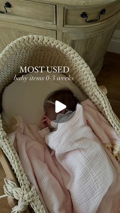 a baby wrapped in a pink blanket is laying in a wicker basket on the floor