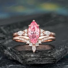 a pink diamond ring sitting on top of a rock with white diamonds around the band