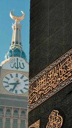 an ornate clock tower with arabic writing on it's sides and a large building in the background