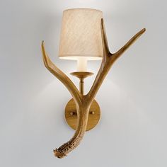 a deer antler wall light with a white shade on it's head and the bulb turned off