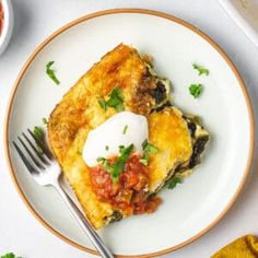 a white plate topped with an omelet covered in toppings and a fork