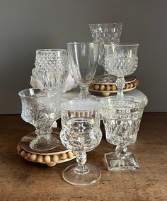 an assortment of glass dishes and glasses on a wooden table with beads around the edges