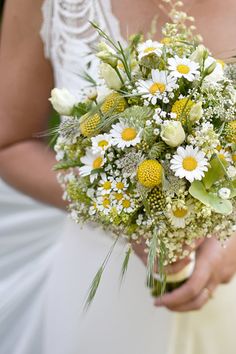 a bride holding a bouquet of white and yellow flowers