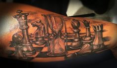 a man's arm with chess pieces and an hourglass tattoo on the arm