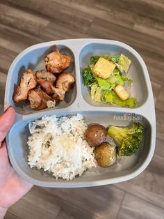 a person holding a tray with rice, broccoli and chicken