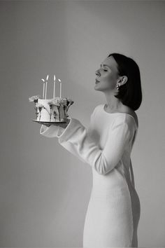 a woman holding a cake with candles on it in front of her face and looking up at the sky