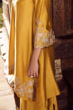 Introducing the sona patti hukum kurta, crafted from the finest mustard linen, a seamless blend of tradition and modernity. This set features intricate floral and paisley appliqué work on a canvas of chanderi, exuding elegance and sophistication. The three-quarter sleeve, v-neck kurta is paired with a voluminous drape skirt, creating a silhouette that captures the essence of the eclectic, empowered modern woman. Whether it's for family functions or ethnic occasions, this two-piece staple is a mu Applique Work Kurti, V Neck Kurti Design, Appliqué Work, Co Ords Outfits, Kurti Style, Kurti Patterns, Pakistani Fashion Casual, Pakistani Fashion Party Wear, Indian Dresses Traditional