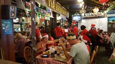 people sitting at tables in a restaurant with christmas hats on their heads and eating food