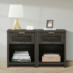 a night stand with two books and a lamp on it next to a white wall