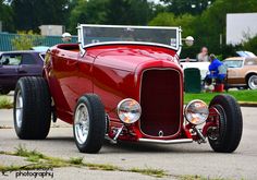 an antique red car is parked on the street