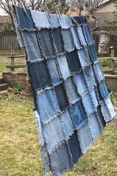 an old pair of jeans is hanging on a clothes line in a yard with grass and trees