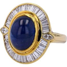 Behold, a marvel of opulence and elegance that transcends the ordinary - a stunning 18K Yellow Gold ring featuring a mesmerizing 10.46-carat cabochon sapphire sourced from the exotic lands of Thailand. This masterpiece is not just a piece of jewelry; it is a testament to the grandeur and sophistication that defines you. The rich, deep blue sapphire is encased in a halo of 1.60 carats of dazzling diamonds, meticulously set to enhance the allure of the central stone.Each diamond, carefully selected for its clarity and brilliance, frames the sapphire in a radiant display of light and luxury. The unique cabochon cut of the sapphire, known for its smooth, rounded shape, allows the stone to exhibit an unparalleled depth of color and luster, drawing every eye in the room to its captivating beauty Sapphire Birthstone, Sophisticated Jewelry, Diamond Birthstone, Radiant Diamond, Sapphire Diamond Ring, 18k Yellow Gold Ring, Halo Diamond Ring, Elegant Ring, Unique Gemstones