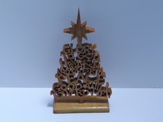 a christmas tree made out of wooden letters with a star above it on a white surface