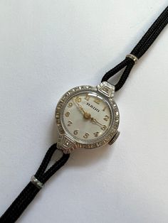 RADO Diamond & 14k White Gold Ladies Vintage Cocktail Wristwatch. c.1950s Lovely 14k white gold case having 20 diamonds set to front bezel and strap shoulders on black cordette strap. Silvered dial signed 'Rado' having guilded numerals and guilded hands. Swiss lever movement signed 'Rado Watch Co Swiss 17 jewels' Outside of back case cover having '14k solid gold' This watch is in beautiful condition. Watch dimensions - 18mm diameter. Length including case lugs 25mm. Strap to fit 150mm. PLEASE NOTE - If you require a shorter or longer strap please let us know as this can be changed no extra charge. This watch is sold with a 12 month guarantee from MBHI certificated watchmakers, established 1947. All watches will be serviced before shipping hence the 2-3 week dispatch. Please note - Watches Classic White Gold Watch With Adjustable Band, Rado Watch, Vintage Cocktail, Gold Case, Womens Watches, Solid Gold, Wrist Watch, Case Cover, Jewelry Watches