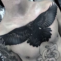 a man's chest with a black bird tattoo on it and an ornate border around the chest