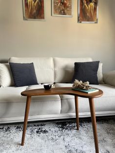 a living room with two paintings on the wall and a coffee table in front of it