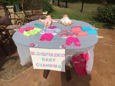 a table with clothes on it and a sign that says blindfolded baby changing