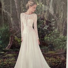 a woman in a wedding dress standing in the woods