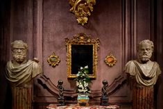 three marble busturines stand in front of a table with flowers and vases on it