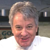 a man in a chef's coat is smiling at the camera while wearing a white shirt and tie