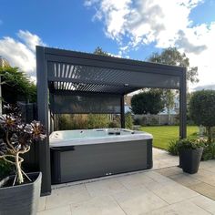 a large hot tub sitting in the middle of a garden next to a pergolated area