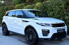 a white range rover parked in front of some bushes