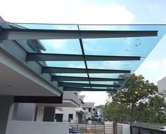 a glass roof over a white fence in front of a building with cars parked on the street