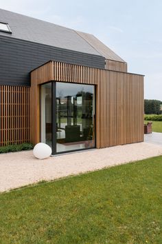 a modern house with wood siding and glass doors on the outside, along side a grassy lawn