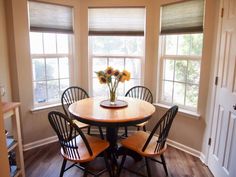 a dinning room table with four chairs and a vase of flowers on the table