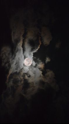 the full moon is seen through clouds in this dark night time photo, taken from an airplane