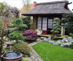 a japanese garden with green grass, rocks and water feature in the center is a small gazebo