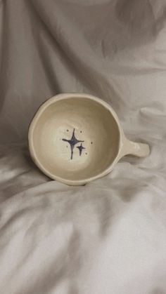 a white bowl with an airplane drawn on the side sitting on a bed covered in sheets