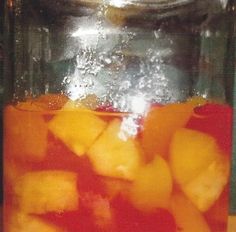 a glass jar filled with fruit sitting on top of a table