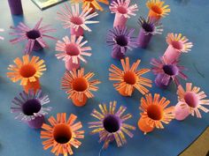 paper flowers are arranged on a table with purple and orange sticks sticking out of them