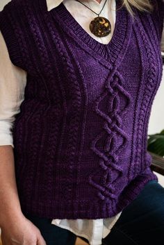 a woman wearing a purple sweater vest and necklace