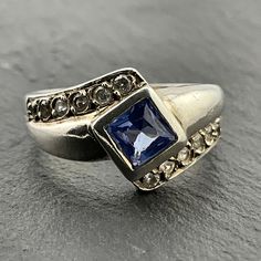 Vintage Blue & White Cubic Zirconia Sterling Silver Fancy Twist Square Statement Ring, UK Size N1/2, US Size 6 3/4, EU Size 53 1/4, Stamped SIL, Front Max Width 11.8mm, Weight 4.53 Grams, Lovely Condition Vintage Blue Sapphire Ring With Diamond Accents, Blue Diamond Rings With Sparkling Stones, Blue Costume Jewelry For Anniversary, Classic Rhinestone Rings For Formal Occasions, Blue Diamond Jewelry With Rhinestones, Classic Formal Rings With Rhinestones, Elegant Sapphire Rings With Sparkling Stones, Classic Formal Rhinestone Rings, Formal Sapphire Jewelry With Rhinestones