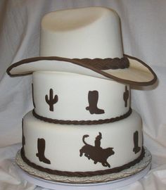 three tiered cake decorated with cowboy hats and cowgirl silhouettes on white fabric