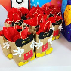 there are many bags that have mickey mouse on them and some red paper bags in front of them