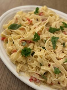 a white plate filled with pasta and garnished with parsley on the side