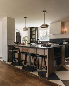 a kitchen with black and white checkered flooring, two bar stools at the island