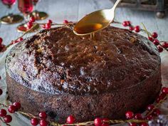 a chocolate cake with cranberries and a spoon in it, on a table