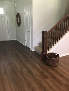 a wooden floor in a house with stairs and a basket on the ground next to it