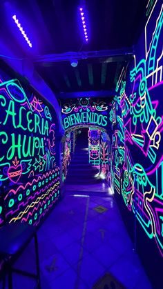 an illuminated tunnel with neon writing on the walls