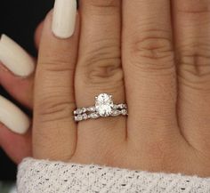 a woman's hand with two wedding rings on her fingers and a white manicure